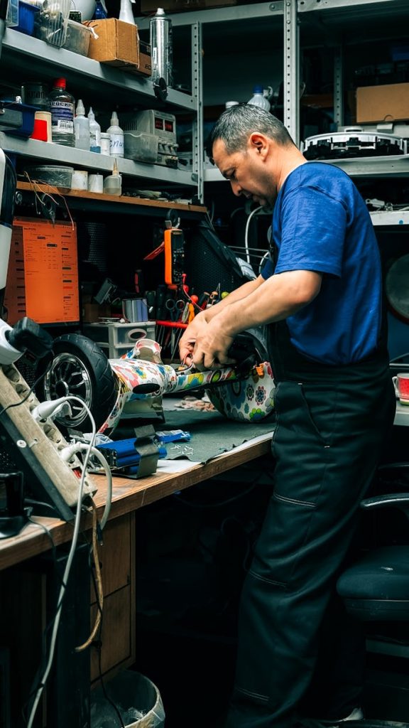 Adult man repairing electronics in a cluttered workshop indoors. Technical work environment.